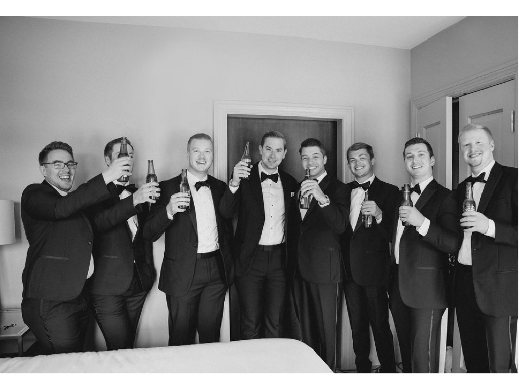 Groom and groomsmen celebrate in hotel room