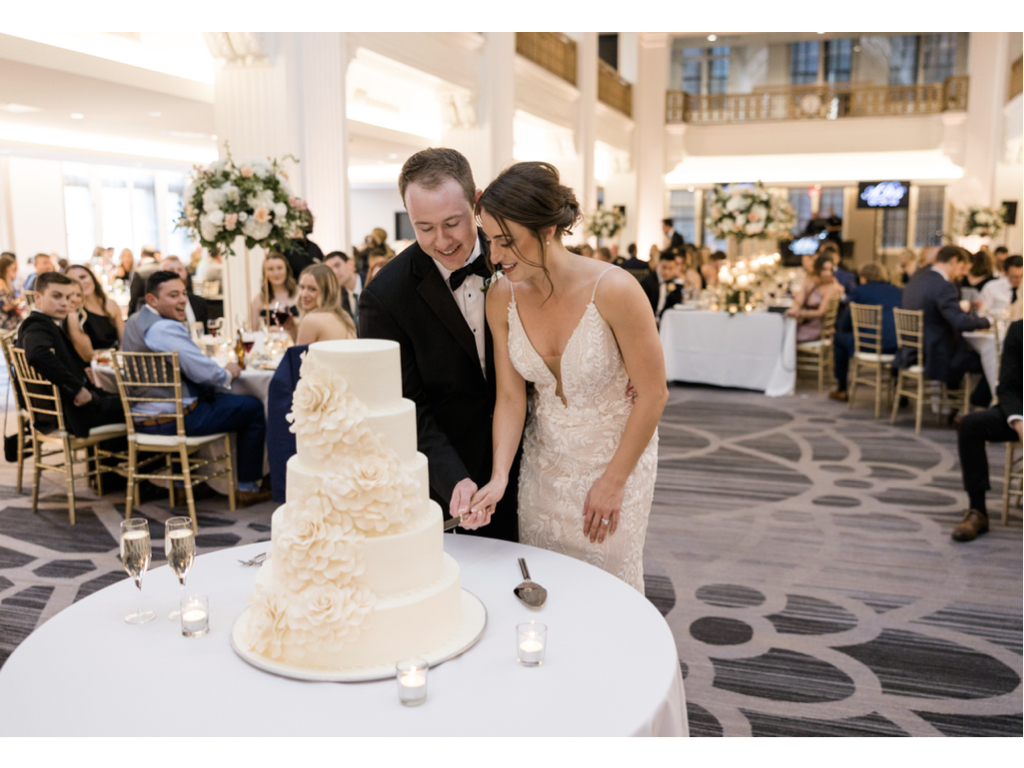 Bride and groom cutting wedding cake in a ballroom